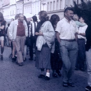 Busy European street scene with pedestrians and cars.