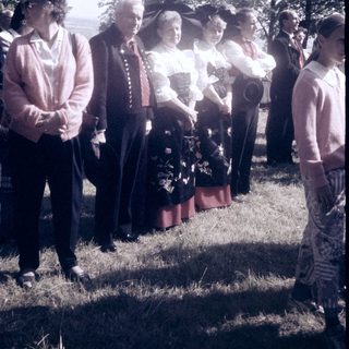 Group of people in outdoor ceremony with floral tribute.