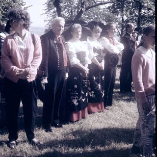 Group of people in outdoor ceremony with floral tribute.