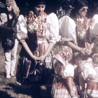 Group of women and children outdoors in traditional folk attire.