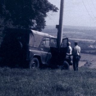 Rural landscape with two people near truck.