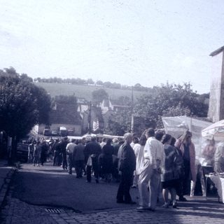 Vintage outdoor market with crowd and stalls.