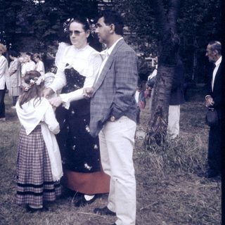 Mid-20th-century outdoor event with formal attire and floral decorations.
