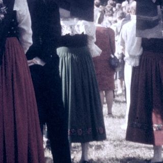 Traditional folk costumes in outdoor gathering near church.