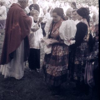 Traditional folk gathering with priest blessing attendees.