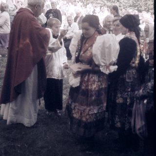 Traditional folk gathering with priest blessing attendees.