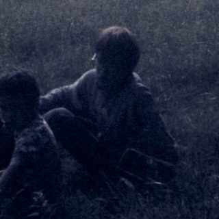 Soldiers resting in rural field during wartime.