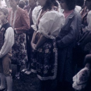 Outdoor religious blessing ceremony with priest and children.