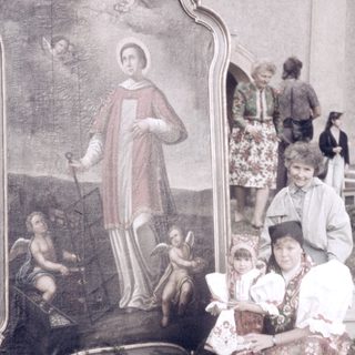 Family posing with religious mural outside.