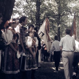 People in traditional and formal attire holding flags outdoors.