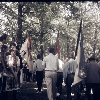 People in traditional and formal attire holding flags outdoors.