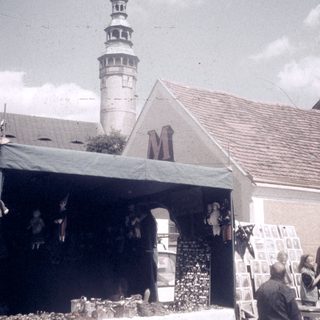 Street market stall with musical performance near historic tower.