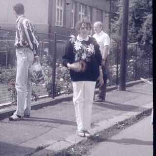 People walking near a two-story house with a gated garden.