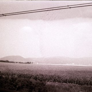 Rural landscape with distant hills, open fields, and power lines.