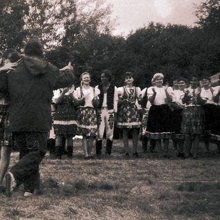 Traditional folk dance performance outdoors in historical attire.