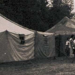 Outdoor gathering with tents and open-air event.
