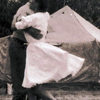 Couple dancing outdoors near tents.