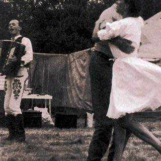 Couple dancing outdoors near tents.