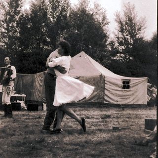 Couple dancing outdoors near tents.