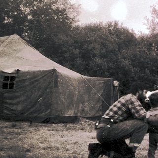 People camping outdoors in tents with children.