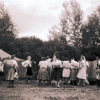 Group in traditional folk costumes dancing outdoors.
