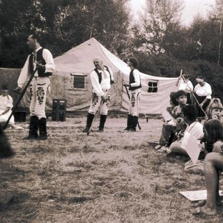 Medieval reenactment scene with performers and audience.