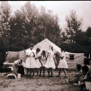 Vintage outdoor gathering with tents and people.