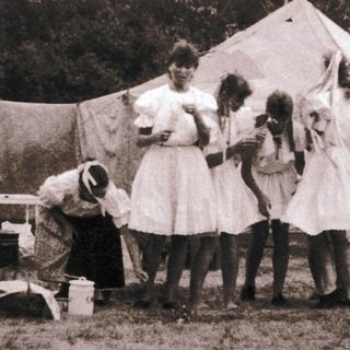 Vintage outdoor gathering with tents and people.