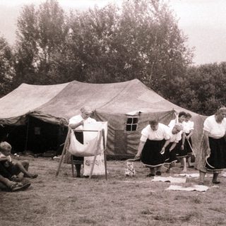 Group of people sewing outdoors near tents.