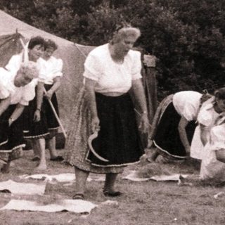 Group of people sewing outdoors near tents.