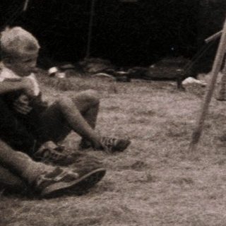 Group of people sewing outdoors near tents.