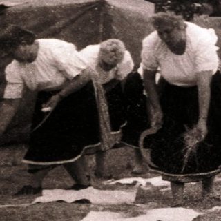 Group of people engaged in traditional rope-making outdoors.