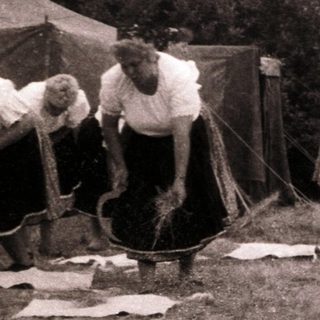 Group of people engaged in traditional rope-making outdoors.