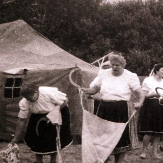 Group of women and girls playing outdoor game with rackets.
