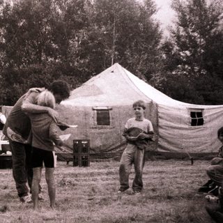 Group camping scene with people gathered around tents.