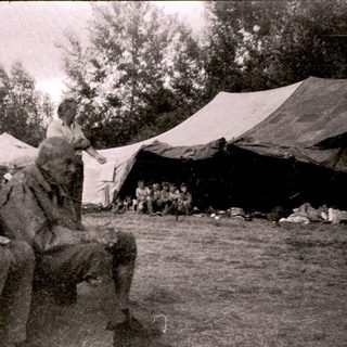 Two elderly men sitting outdoors near tents.