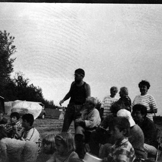 Group of people gathered outdoors at a campsite.