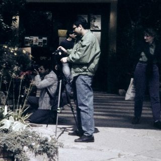 People taking photos near a building with garden flowers.