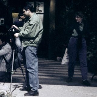 People taking photos near a building with garden flowers.