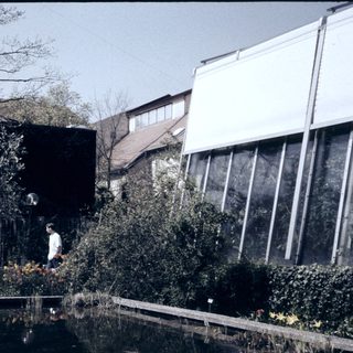 Modern building with reflective glass, pond, and landscaped garden.