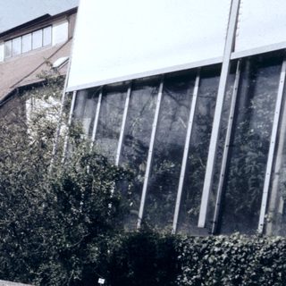 Modern building with reflective glass, pond, and landscaped garden.