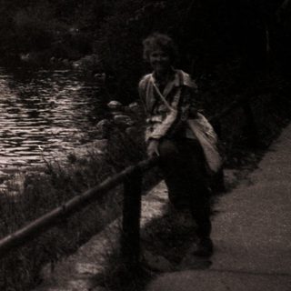 Person standing by serene mountain lake.