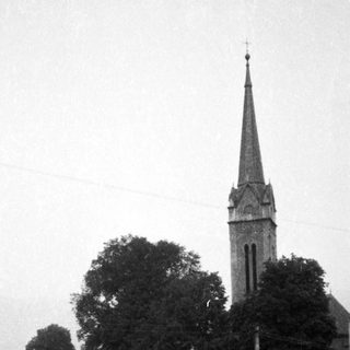 Historic church by river with stone bridge.