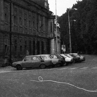 Agrarian town street with old buildings and parked cars.