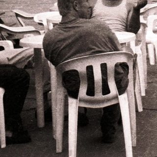 People sitting outdoors near mountains in urban café setting.