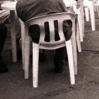 People sitting outdoors near mountains in urban café setting.