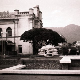 Historic building with modernist sculptures in urban park.