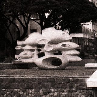 Historic building with modernist sculptures in urban park.