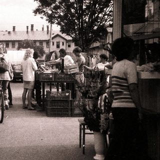 Farmers market with people shopping outdoors.