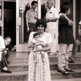 Family gathering outside a building in summer attire.